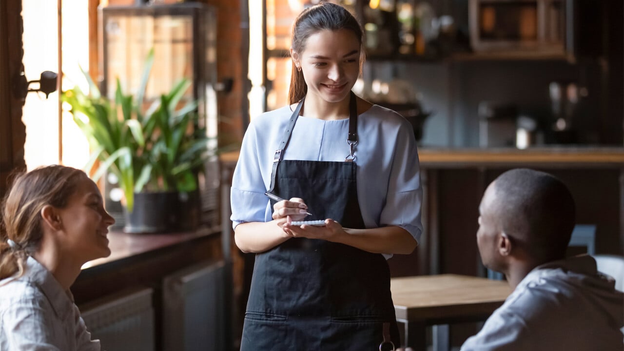 Ung jente som tar i mot bestilling på kafé